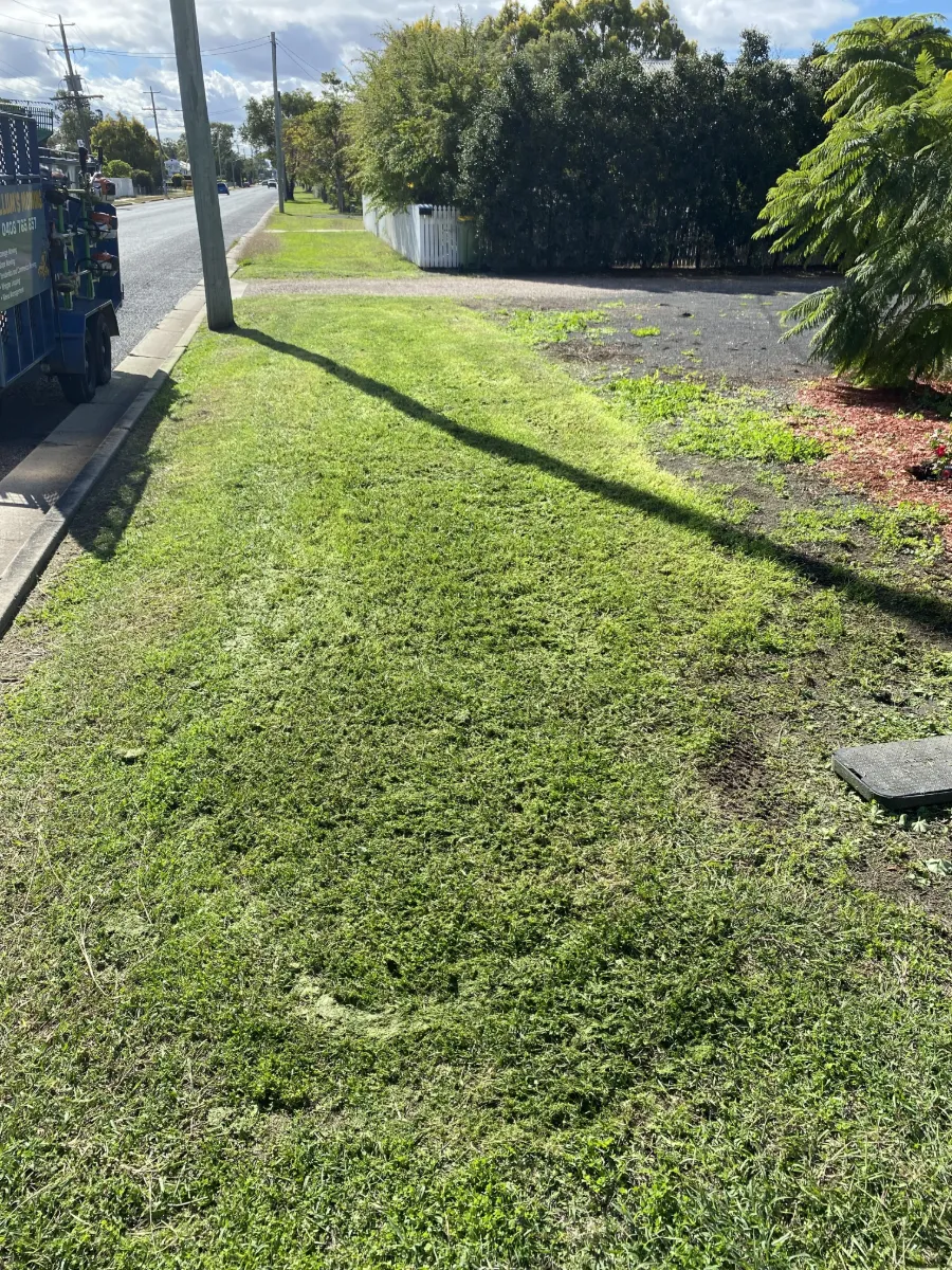Street verge freshly cut and cleaned up beside a Laidley road, with the Callum's Mowing trailer parked at the kerb