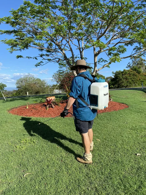 Callum spraying weeds around a garden bed on a Lockyer Valley property